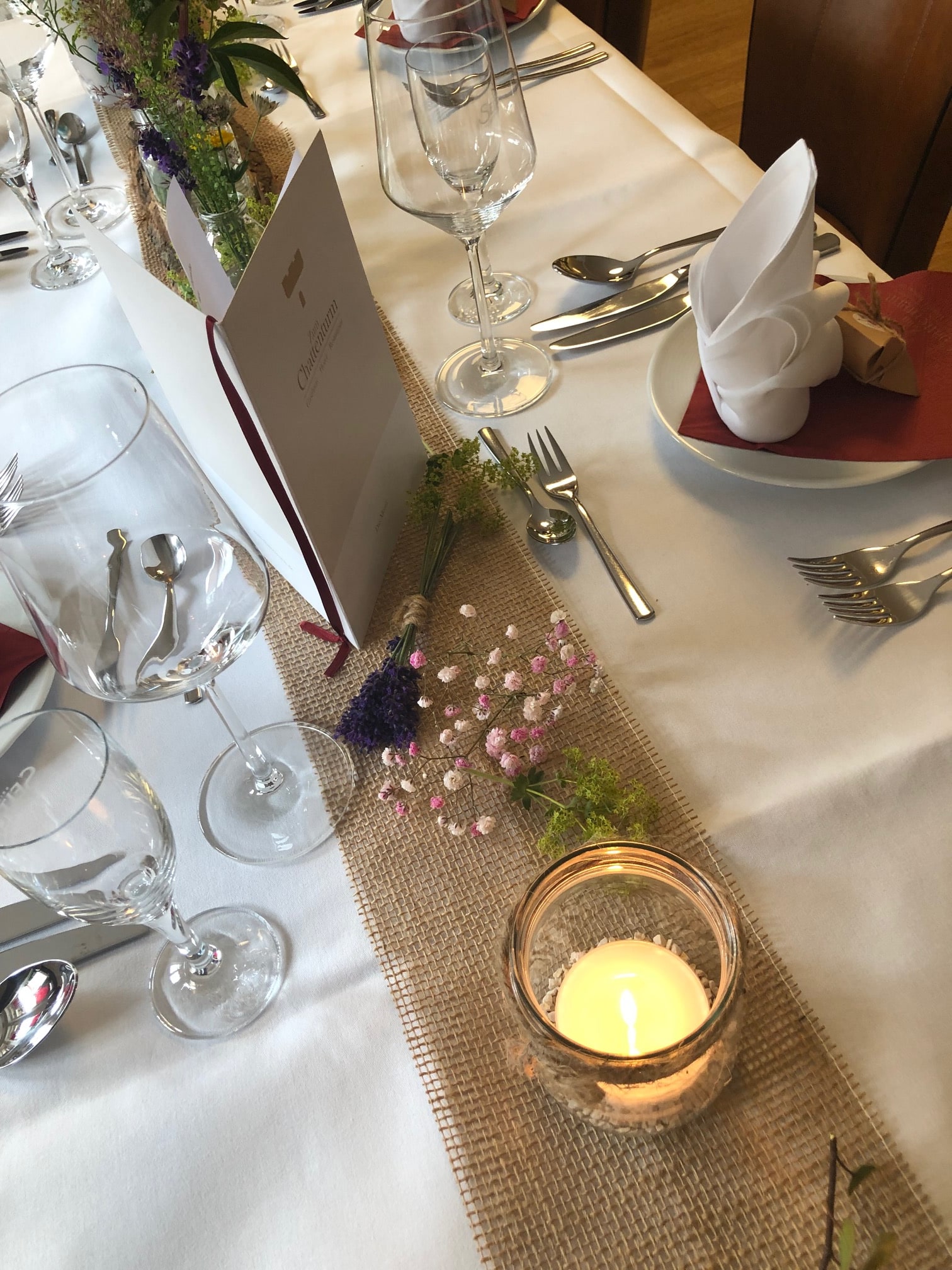 Festlich gedeckter Tisch mit Menükarte, Blumen und Kerzenschein